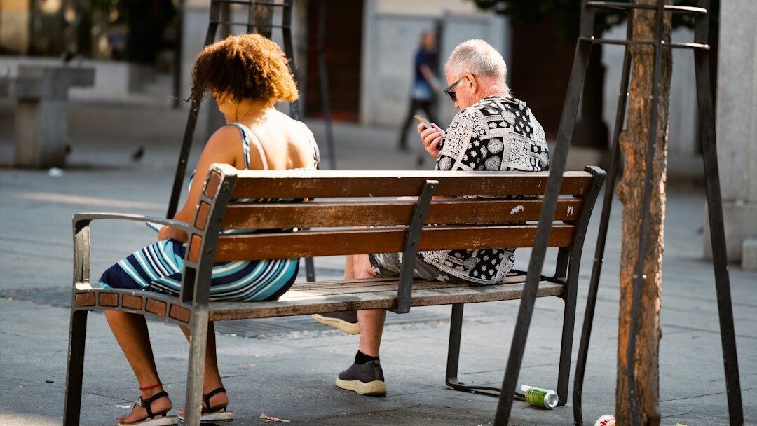 Elderly woman and young interviewer talking on a bench in a Danish town