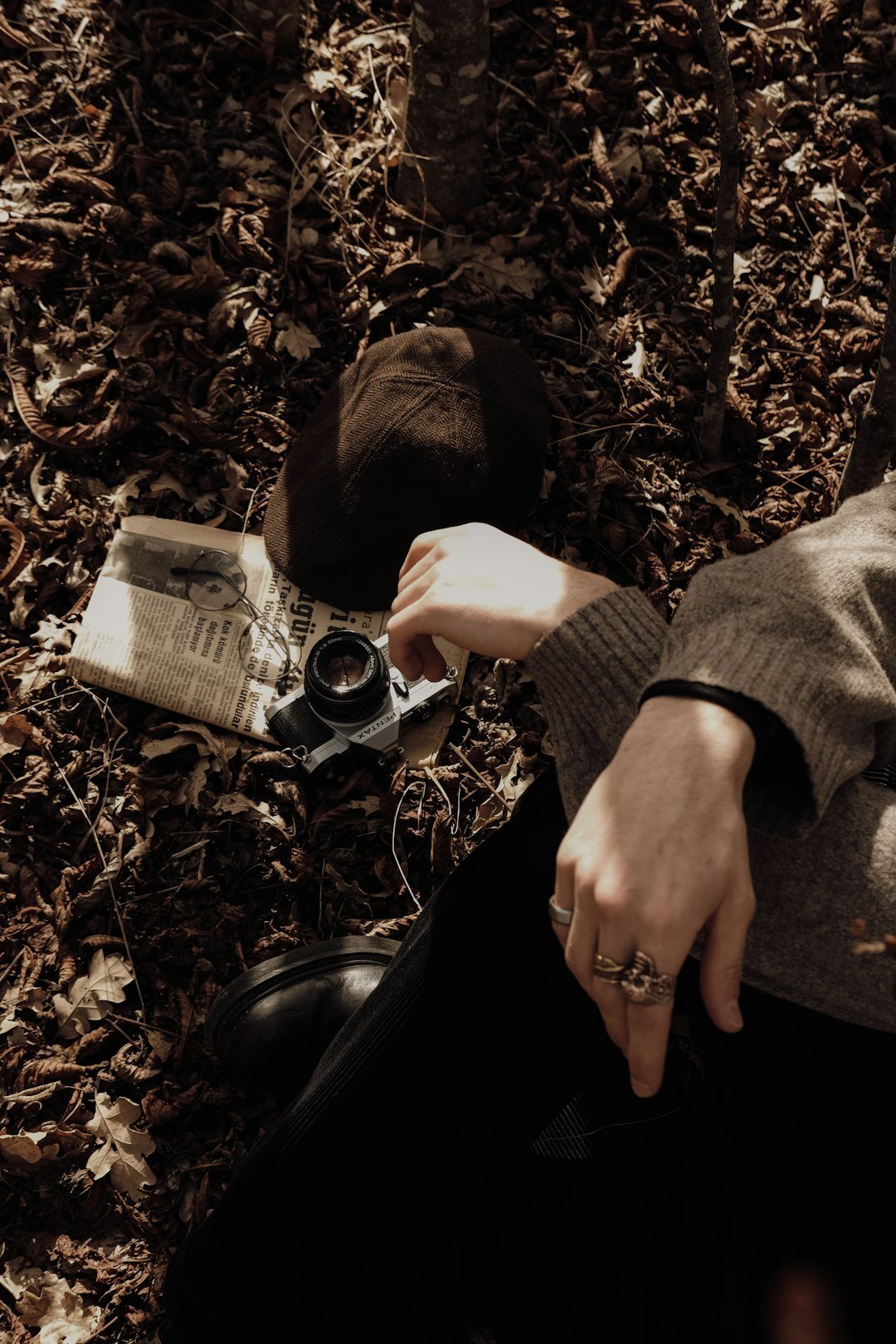 Close-up of hands writing in a notebook next to a coffee cup and camera
