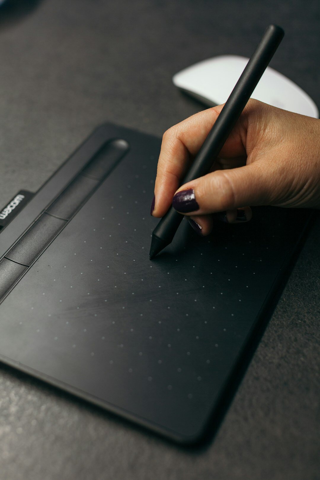 Man writing notes next to a laptop at a wooden desk